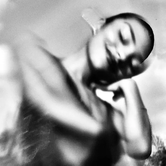 Black and white photo of a person with closed eyes and a slight smile, captured through a blurred lens, creating a soft and dreamy effect.